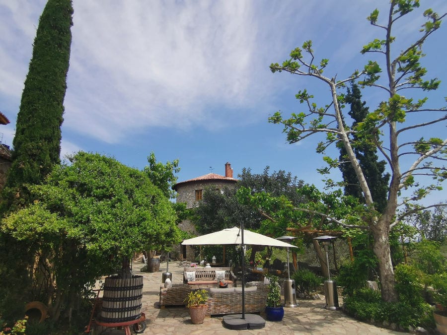 front view of 'La Tour Melas' tower with a old grape press outside and trees